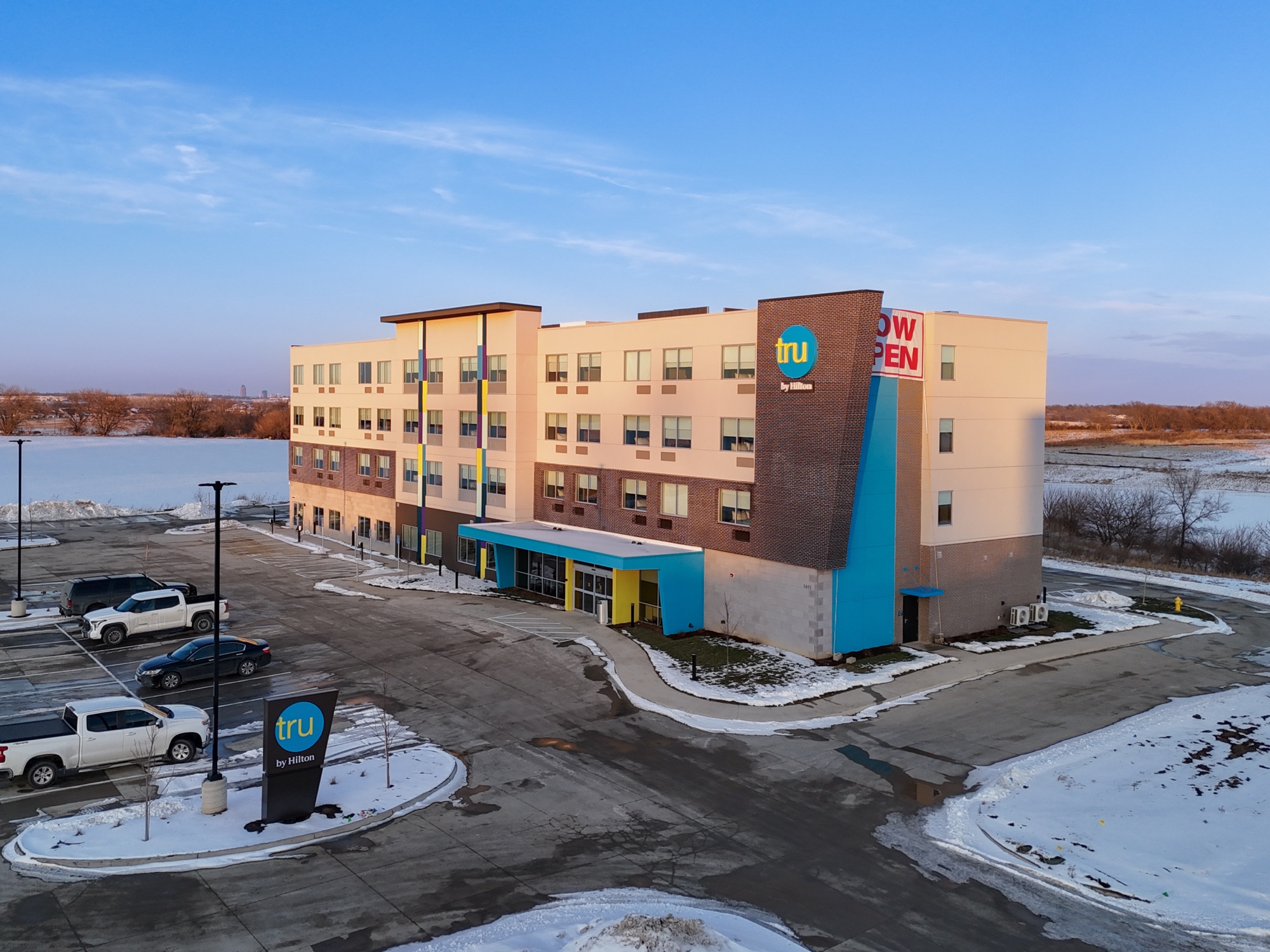 Aerial view of the completed Tru by Hilton Norwalk in Iowa, a four story hotel with the brand exterior color blocking and entry canopy